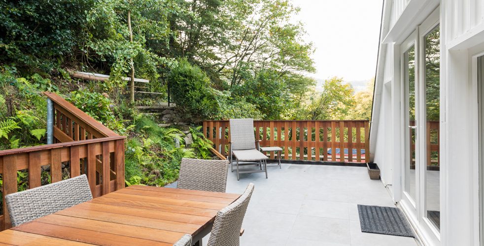 Die Terrasse des Pfeffertürmchens mit Holztisch, Liegestuhl und Blick ins Grüne